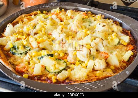 Hausgemachte vegetarische Veggie-Pizza mit Käse, Ananas, Mais, Gemüse, Zucchini, Blumenkohl in Backblech-Form Stockfoto