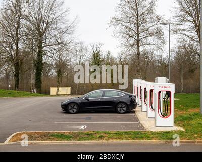 UNBEKANNTE AUTOBAHNSTATION, FRANKREICH - 9. MÄRZ 2020: Ladestation für Elektroautos, mit einem Auto. Tesla. Stockfoto