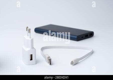 Getrenntes weißes USB-Netzteil, Kabel und blaue Powerbank für Trennstellen auf weißem Hintergrund. Stockfoto