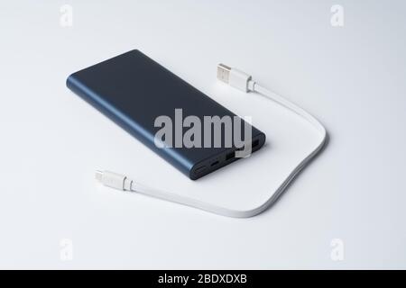 Weißes USB-Kabel und blaue Powerbank getrennt, um den Divice auf weißem Hintergrund zu isolieren. Stockfoto