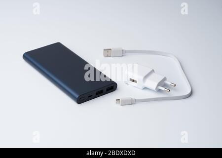 Getrenntes weißes USB-Netzteil, Kabel und blaue Powerbank für Trennstellen auf weißem Hintergrund. Stockfoto