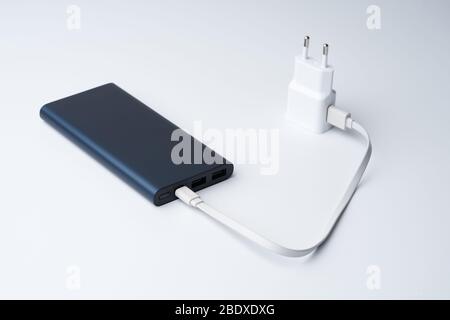 Angeschlossenes weißes USB-Netzteil, Kabel und blaue Powerbank für Divice isoliert auf weißem Hintergrund. Stockfoto
