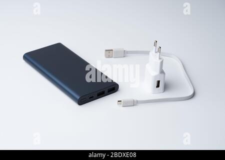 Getrenntes weißes USB-Netzteil, Kabel und blaue Powerbank für Trennstellen auf weißem Hintergrund. Stockfoto