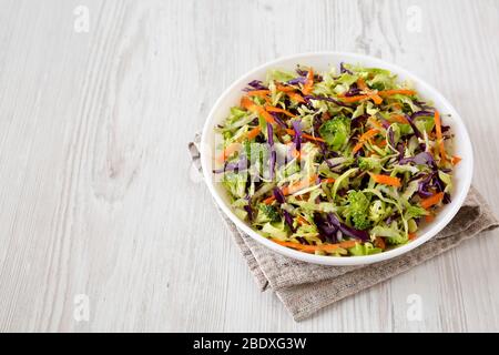 Hausgemachte Raw zerfetzte Broccoli Slaw in einer weißen Schüssel auf Tuch, Seitenansicht. Kopierbereich. Stockfoto