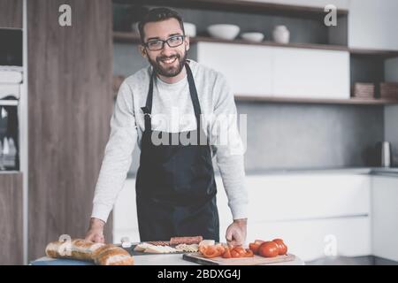 Mann in eine Schürze in Scheiben Salami Sandwiches Stockfoto