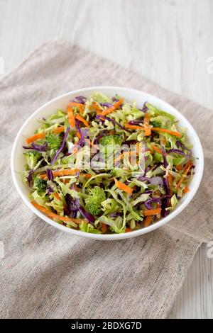 Hausgemachte Raw zerfetzte Broccoli Slaw in einer weißen Schüssel auf Tuch, niedrige Winkel Ansicht. Nahaufnahme. Stockfoto