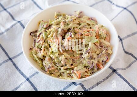 Hausgemachte cremige Broccoli Slaw in einer weißen Schüssel auf Tuch, Seitenansicht. Nahaufnahme. Stockfoto