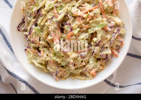 Selbstgemachte cremige Broccoli-Slaw in einer weißen Schüssel auf Tuch, Blick von oben. Flach liegend, Ansicht von oben, von oben. Nahaufnahme. Stockfoto