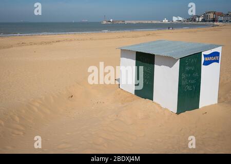 Kreideschreiben, die Menschen sagen, sich vom Margate Beach fernzuhalten, ist an einem leeren Strand in Margate, Kent, während des Osterfeiertags sichtbar, während Großbritannien weiterhin in der Sperre bleibt, um die Ausbreitung des Coronavirus einzudämmen. Stockfoto