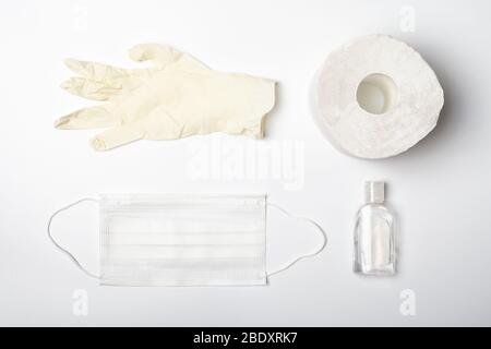 Sterilisierte medizinische Gesichtsmaske, antiseptisches Händedesinfektionsmittel, Gummihandhandschuhe und Toilettenpapier auf weißem Hintergrund. Medizinische Grundausstattung für Battl Stockfoto