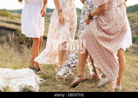 Die Firma der weiblichen Freunde, Spaß, tanzen auf Summerfield in lange Kleid ihre Beine zu zeigen. Sommer ländlichen Stil Picknick Konzept Stockfoto