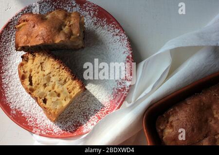 Frisch gebackener traditioneller Apfel-charlotte-Pudding in Backform und auf einem Teller mit Puderzucker. Leichter Kuchen zum Frühstück. Draufsicht. Stockfoto