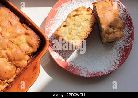 Frisch gebackener traditioneller Apfel-charlotte-Pudding in Backform und auf einem Teller mit Puderzucker. Leichter Kuchen zum Frühstück. Draufsicht. Stockfoto