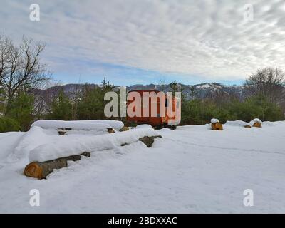 Winterlandschaft irgendwo in den Karpaten, in einer Lichtung eines immergrünen Waldes gibt es eine alte, rostige, verlassene Zugkarre umgeben b Stockfoto