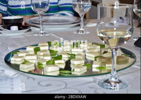 Elegante Einrichtung am Restauranttisch, Nahaufnahme von Weißweingläsern, die zum Verkosten bereit sind, neben Spiegelplatte mit frischen Mozzarella-Käsescheiben Stockfoto