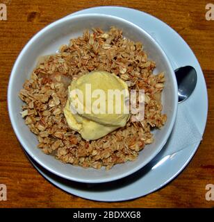 Draufsicht der weißen Schüssel auf dem Tisch mit leckeren Hafer vom Koch mit Vanille-Eis auf der Oberseite vorbereitet gefüllt, gread Dessert Ideen, die gesund und delici sind Stockfoto