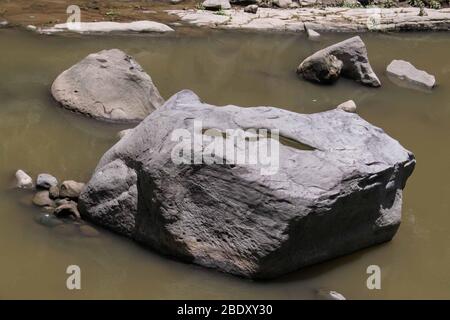 Großer Stein mitten in einem stillen Fluss Stockfoto