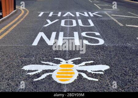 Ein „Danke NHS“-Schild mit einer Biene, dem offiziellen Symbol von Manchester, großbritannien, auf der Straßenoberfläche der Lower Mosley Street, einer Straße neben dem NHS Nightingale Hospital North West, Im Manchester Central Complex wird angesichts des aktuellen weltweiten Ausbruchs des neuartigen Coronavirus Covid 19 ein temporäres Krankenhaus eingerichtet. Stockfoto