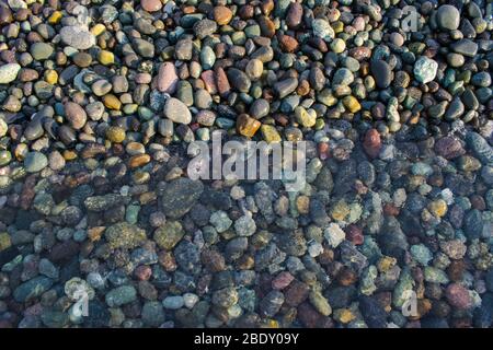 Bunte Kieselsteine unter einem sehr klaren Meerwasser am Meer Stockfoto