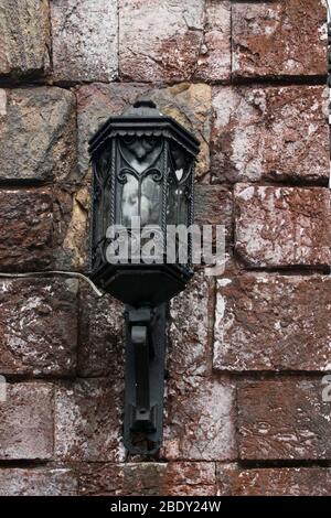 Eine schwarze Vintage Wandlampe an einer rustikalen Ziegelwand Stockfoto