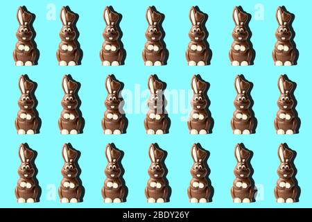 Trendiges Ostermuster aus Schokoladenkaninchen auf blauem Hintergrund im minimalistischen Stil. Osterkonzept im minimalistischen Stil. Stockfoto