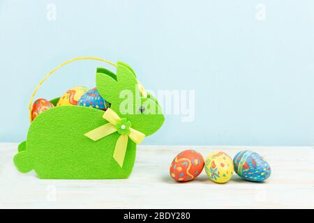Bunte ostereier in einem Hasen-Korb auf blauem Hintergrund. Konzept der Osterferien. Copyspace, Platz für Text Stockfoto