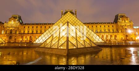 Blick auf das berühmte Louvre Museum mit Louvre Pyramide bei Nacht Stockfoto