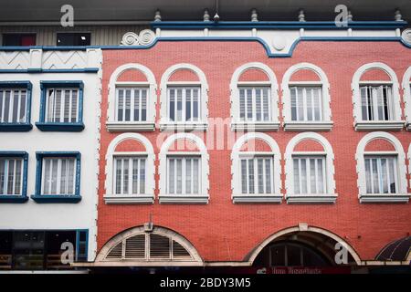 Backsteinhaus mit weiß bemalten Fenstern und Blumentöpfen hängen am Fenster. Französische Designgebäude. Stockfoto