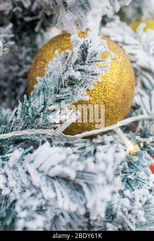 Weihnachten im Hintergrund mit schneebedeckten Zweigen und einem großen golden Christmas Ball in der Mitte. Stockfoto