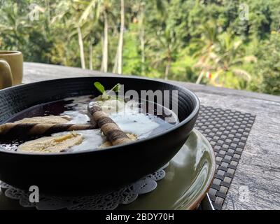 Schüssel mit Karamell-Eis auf weißem Hintergrund. Eis schwimmend auf einem Sirup auf einer schwarzen Schüssel Stockfoto