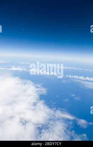 Blick aus dem Fenster eines Flugzeugs auf den Mond, blauen Himmel, Wolken und den Atlantik. Zeigt Erde, Umwelt, globales Konzept Stockfoto