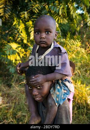 Ein Kleinkind sitzt auf den Schultern seines Bruders im Norden Malawis Stockfoto