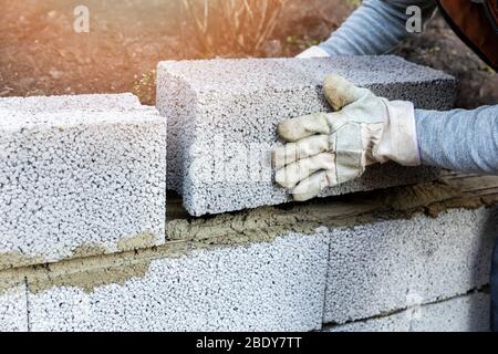 Haus Wandkonstruktion - Maurer Verlegung von Lehmbausteinen Stockfoto