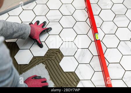 Fliesenleger Verlegung Marmor Textur Sechskant Fliesen auf dem Badezimmerboden Stockfoto