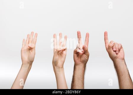 Nahaufnahme Foto eines Mannes und einer Frau Hände isoliert über weißen Wand Hintergrund zeigt Zählen Zahlen durch Finger. Stockfoto