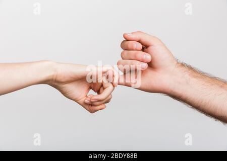 Closeup Bild der Hände eines Mannes und der Frau mit kleinen Finger von einander über weiße Wand Hintergrund isoliert. Stockfoto