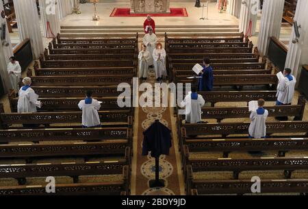 Fr. Kieran McDermot und Mitglieder des Palestrina Choir während der Feier des "Lord's Passion"-Gottesdienstes in der St. Mary's Pro-Cathedral in Dublin am Karfreitag. Liturgien werden über Web-Cam übertragen, um bei der sozialen Distanzierung im Kampf gegen die Ausbreitung des Coronavirus zu helfen. Stockfoto