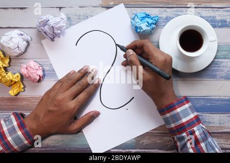 Hohe Winkelansicht des Menschen Hand Zeichnung Fragezeichen. Stockfoto