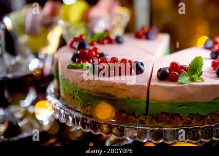 Geschichtete cremige Obstkuchen mit Beeren, Nahaufnahme. Käsekuchen mit Heidelbeeren auf dem Teller. Stockfoto