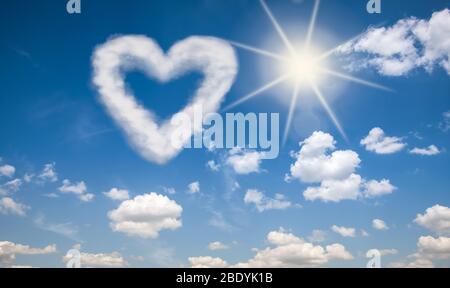 Herzförmige Wolke vor einem sonnigen und blauen Himmel Hintergrund. Liebe ist in der Luft Konzept. Stockfoto