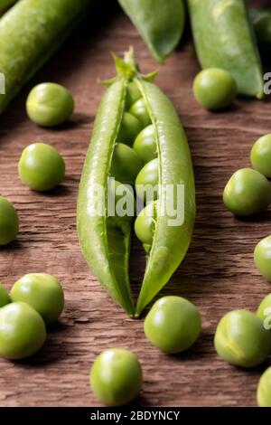 Nahaufnahme von frisch gepflückten Erbsen auf einem Holztisch. Stockfoto