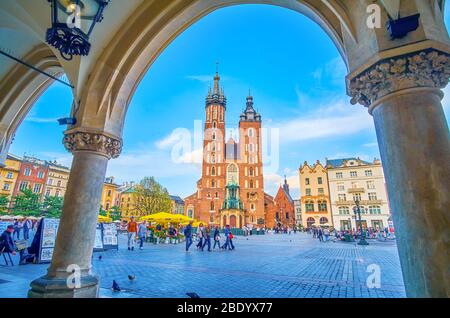 KRAKAU, POLEN - 12. JUNI 2018: Der Blick auf die erstaunliche Marienbasilika auf dem Platz Mariacki durch die Laubengänge von Sukiennice, am 12. Juni in Krakau Stockfoto