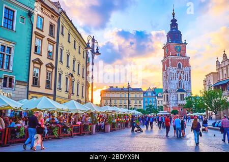 KRAKAU, POLEN - 12. JUNI 2018: Die Abendzeit im Zentrum von Rynek Glowny Platz mit Touristencafés und Menschenmassen, die entlang historischer Orte spazieren, am Juni Stockfoto