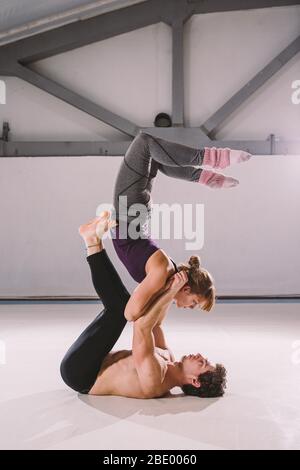 Das Thema von AcroYoga und Yoga stellt. Acroyogis üben. Mit Studio Backlight. Der Mann Base hält in der Static Poses einen Woman Flyer in der Spitze Stockfoto