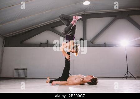 Themensport und ein gesunder Lebensstil. Akrobatik und acroyoga. Junge sportliche Paar üben acroyoga Handstand. Männliche und weibliche Akrobaten tun Stockfoto