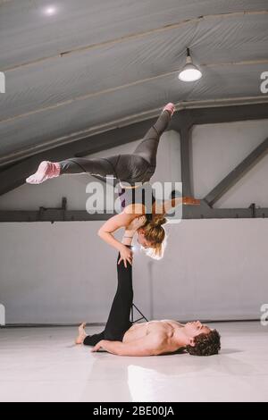 Themensport und ein gesunder Lebensstil. Akrobatik und acroyoga. Junge sportliche Paar üben acroyoga Handstand. Männliche und weibliche Akrobaten tun Stockfoto