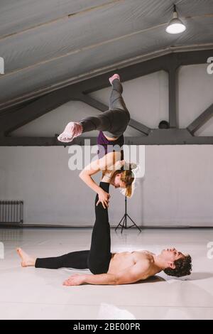 Themensport und ein gesunder Lebensstil. Akrobatik und acroyoga. Junge sportliche Paar üben acroyoga Handstand. Männliche und weibliche Akrobaten tun Stockfoto