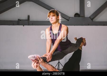 Themensport und ein gesunder Lebensstil. Akrobatik und acroyoga. Junge sportliche Paar üben acroyoga Handstand. Männliche und weibliche Akrobaten tun Stockfoto