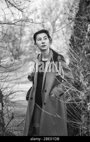 Porträt eines schönen Mädchens im Park bei warmem Herbstwetter. Eine junge Frau geht im Frühlingswald. In warmen Farben getönte. Schwarz-Weiß-Foto Stockfoto