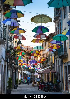 Farbige Sonnenschirme hängen in der engen Straße von Viana do Castelo Nord Portugal Stockfoto